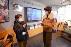 馬の資料館で旋丸専務理事（左）からばんえい競馬の成り立ちについて説明を受けるアンジーさん