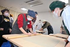 真剣な様子で麺棒を使って生地を均一に伸ばす参加者