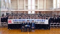 全校生徒との記念撮影に納まる牧野投手(前列中央、須貝拓也撮影)