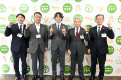 今シーズンの成績である1勝1セーブ1HPにちなんで人差し指で「1」をつくる片山投手(中央)を祝福する小野町長(右から2人目)、福地教育長(右)、山本部長(同4人目)、戸田課長(左)