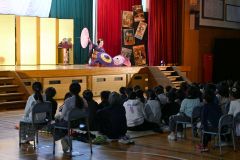 和妻のパフォーマンスに魅入る児童ら