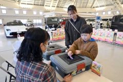 抽選会でスクラッチカードを引く子ども(13日午前11時40分ごろ。帯広市内の日産ドーム店で。金野和彦撮影)