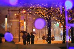 イルミネーションがともった12月の中心街で傘を差しながら歩く住民(14日午後6時ごろ、帯広駅北口で。塩原真撮影)