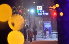 イルミネーションがともった12月の中心街で傘を差しながら歩く住民(14日午後6時ごろ、帯広駅北口で。塩原真撮影)