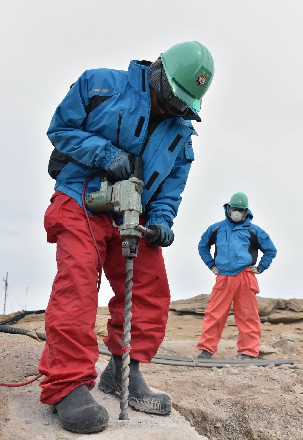 ドリルで岩盤を掘る調理の長谷川隊員（左）と同行者の渡辺さん(2015/12/28)