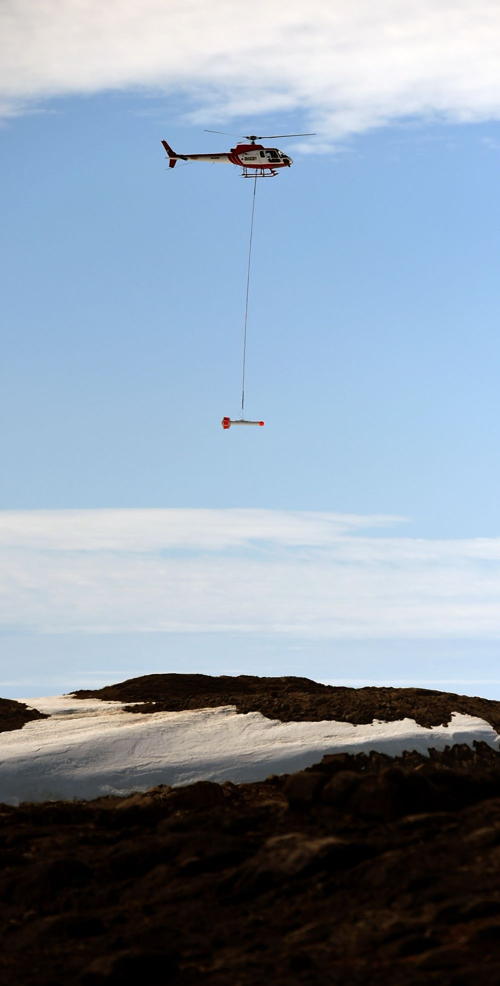 観測機器をつって海氷上を飛ぶヘリコプター(１月１０日）