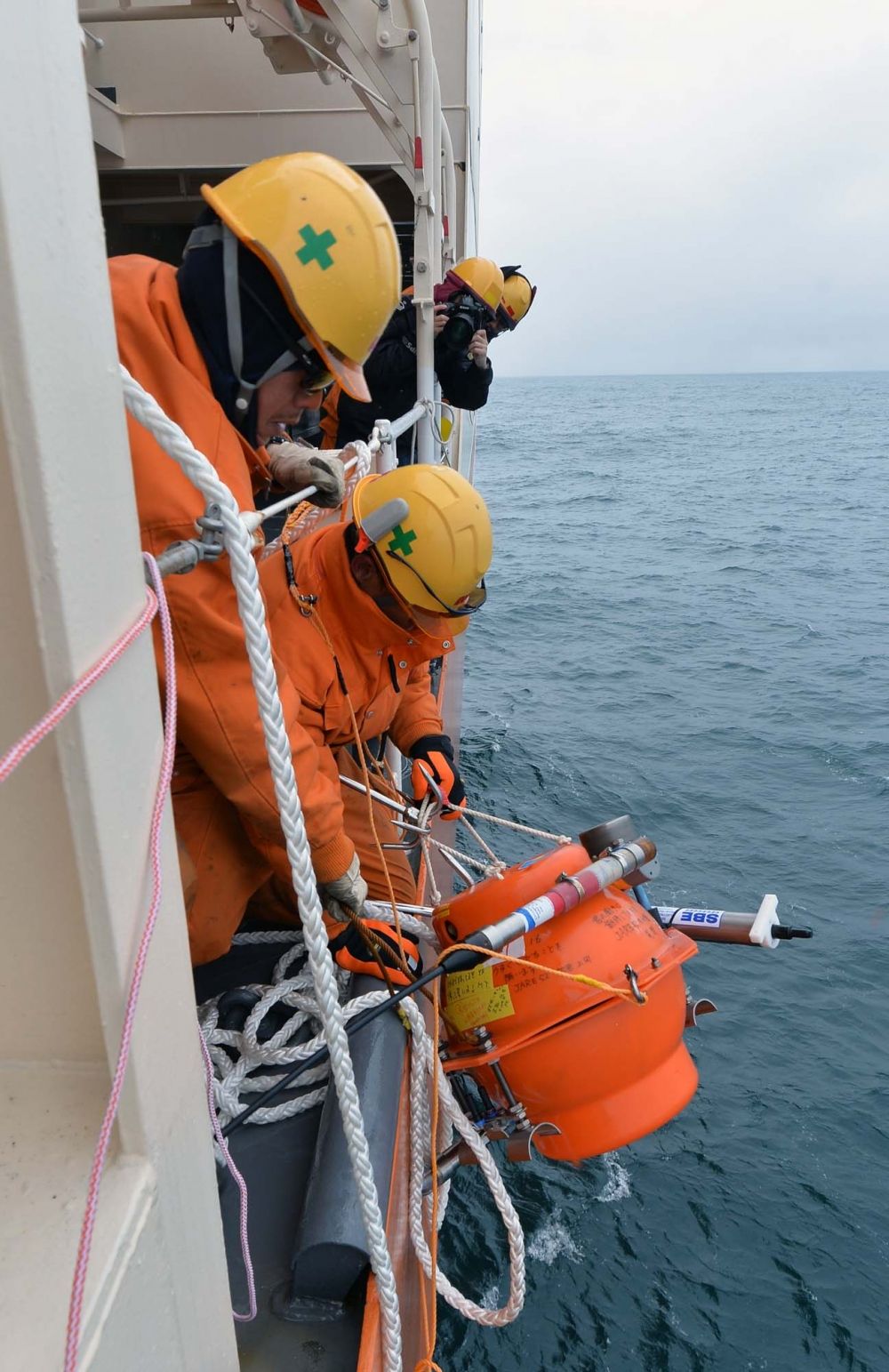 浮上した海底圧力計を船内に回収する自衛隊員